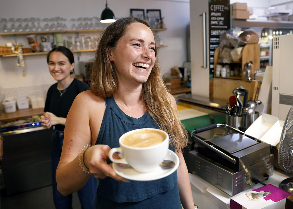 A smiling waitress serving a coffee