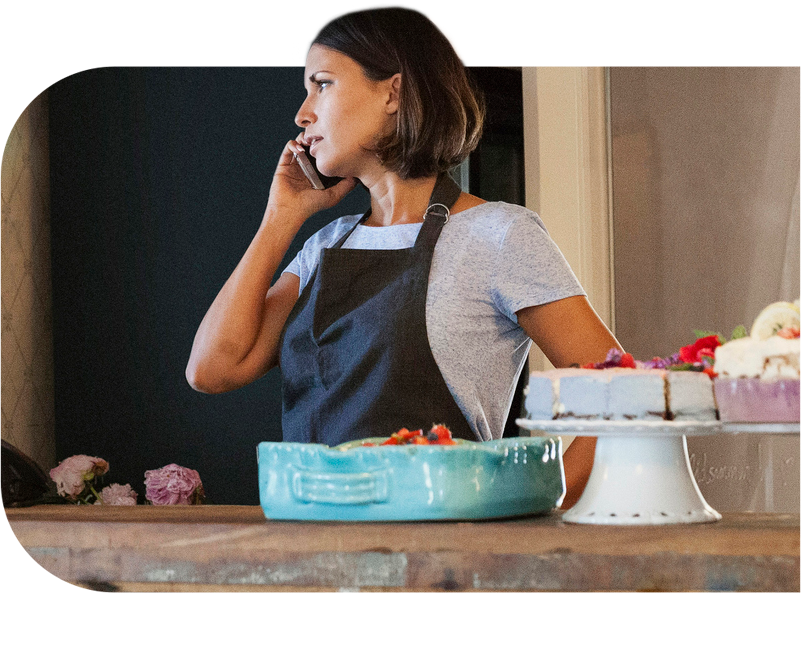 Serious woman talking on phone while standing by counter at cafe